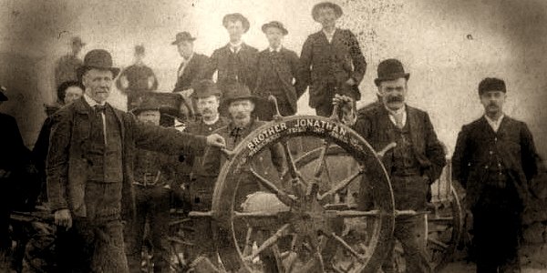 Period photograph of men gathered around the ship's wheel of the Brother Jonathan