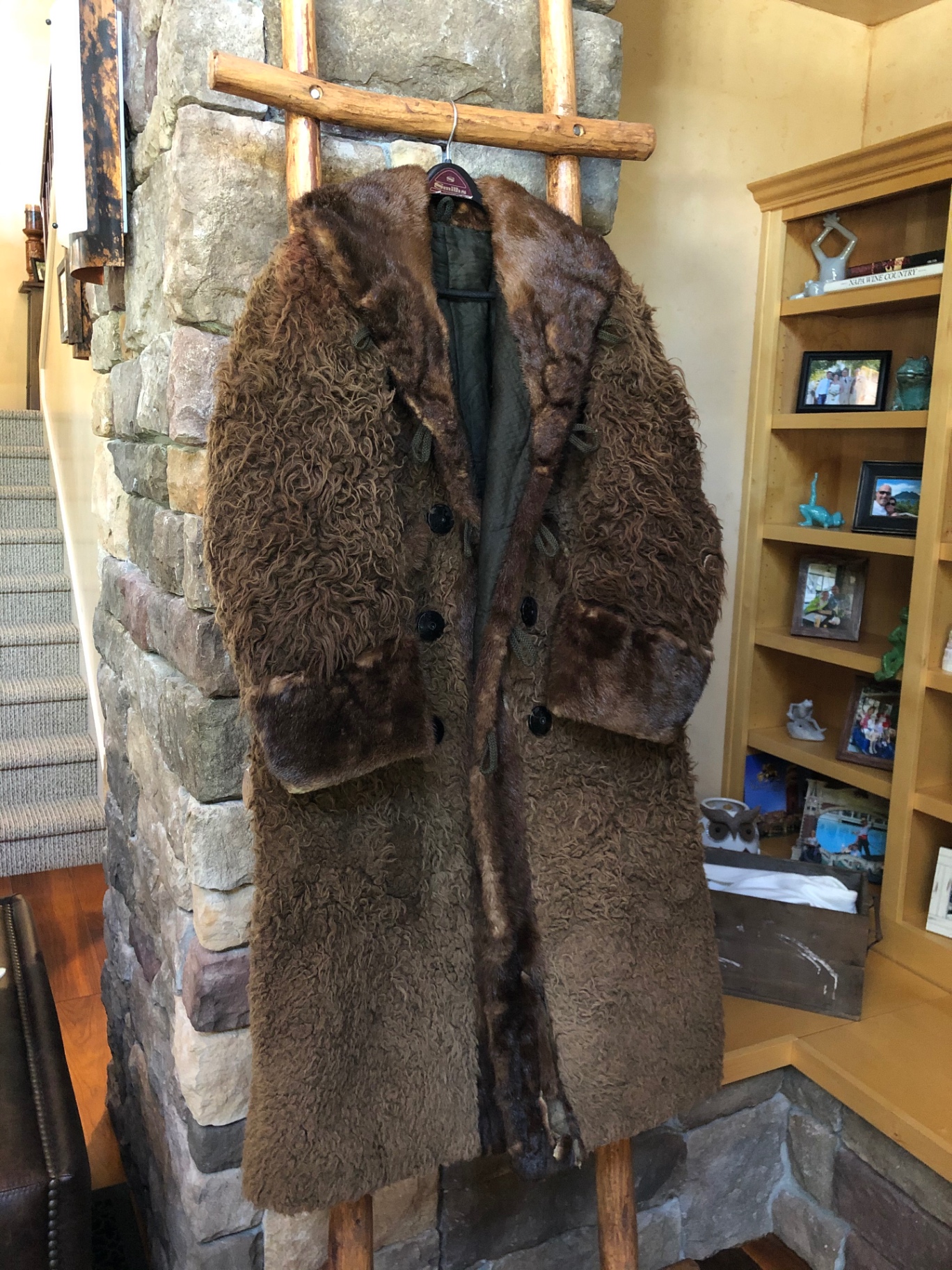 Perry Engle's long curly buffalo and beaver fur coat, hanging on a hand-hewn ladder against a stone fireplace